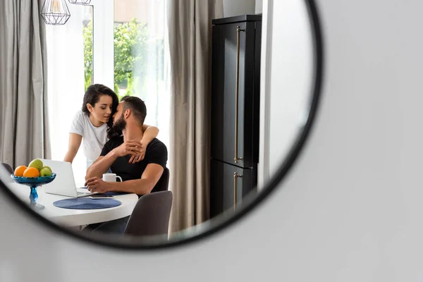 Selective focus of mirror with reflection of attractive girl hugging handsome boyfriend — Stock Photo