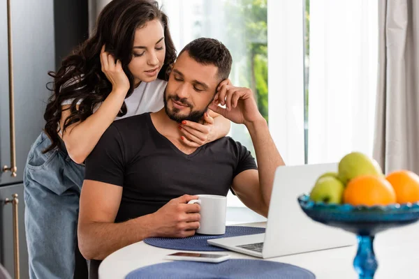 Selective focus of beautiful woman hugging boyfriend with cup of coffee — Stock Photo