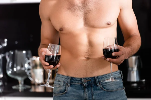 Обрезанный вид мускулистого человека с бокалами красного вина — стоковое фото