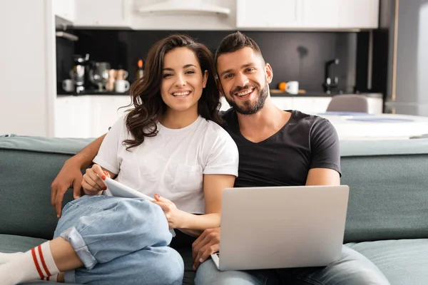 Heureux jeune couple regardant caméra et tenue gadgets — Photo de stock