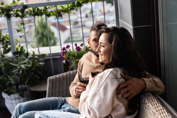 Bearded man hugging cheerful girl with glass of red wine outside — Stock Photo