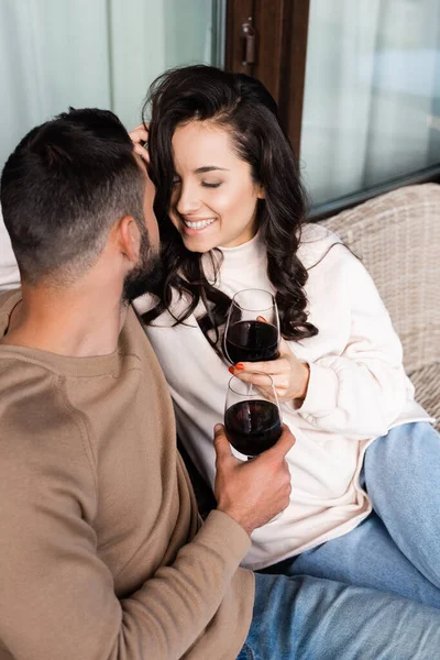 Fröhliche Frau hält Weinglas in der Hand und lächelt neben Freund — Stockfoto