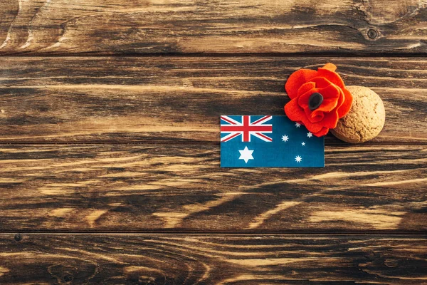 Vista superior da bandeira australiana perto de flor artificial e biscoito na superfície de madeira — Fotografia de Stock