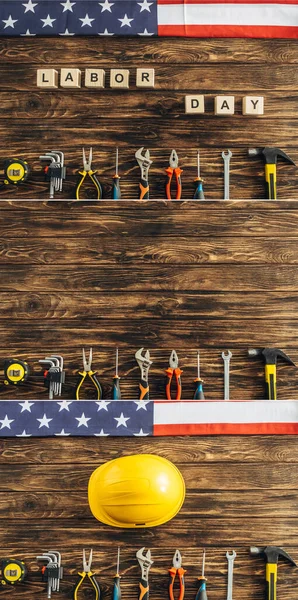 Collage of instruments, safety helmet and american flags near cubes with labor day lettering on wooden surface — Stock Photo