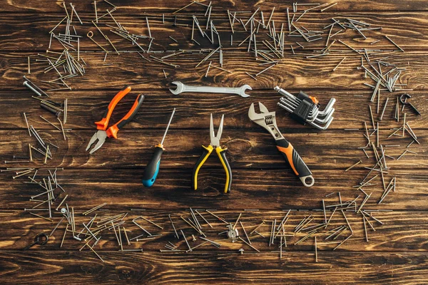 Draufsicht auf metallische Nägel in der Nähe von Instrumenten auf Holzoberfläche, Arbeitstagskonzept — Stockfoto