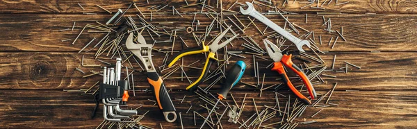 Panoramic shot of instruments and metallic nails on wooden surface, labor day concept — Stock Photo