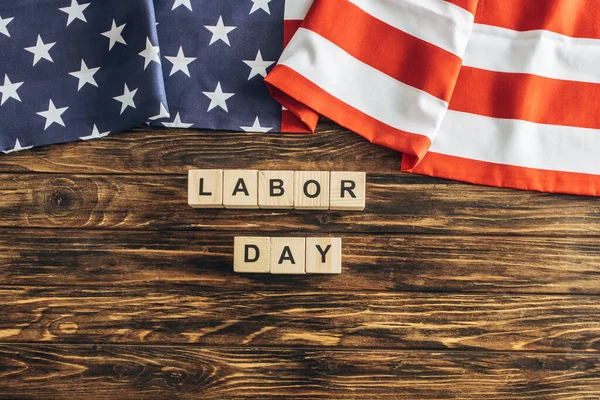 Top view of american flag with stars and stripes near cubes with labor day lettering on wooden surface — Stock Photo