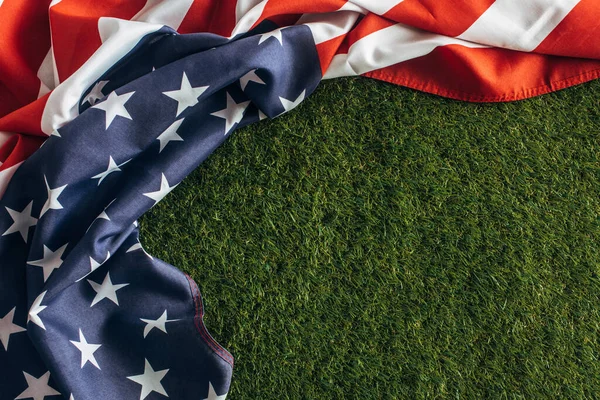 Vista superior de la bandera americana con estrellas y rayas en la hierba verde afuera, concepto del día del trabajo - foto de stock