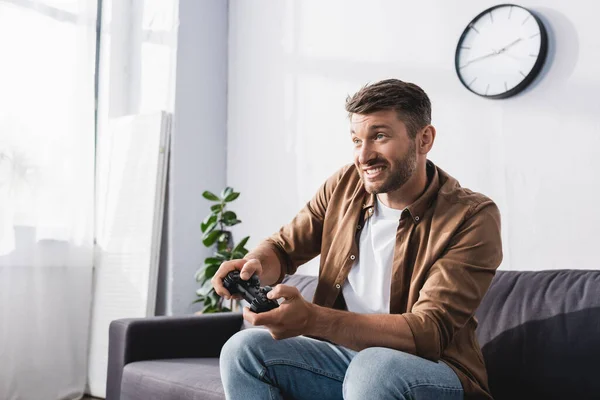 KYIV, UCRANIA - 9 de junio de 2020: hombre emocionado jugando videojuegos con joystick en casa - foto de stock