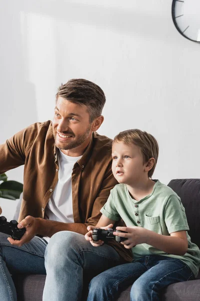 KYIV, UKRAINE - JUNE 9, 2020: excited father and son playing video game with joysticks — Stock Photo