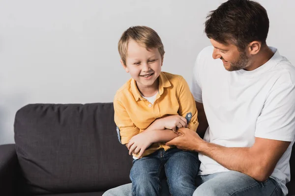 Glücklicher Junge sitzt mit geschlossenen Augen auf dem Schoß eines lächelnden Vaters — Stockfoto