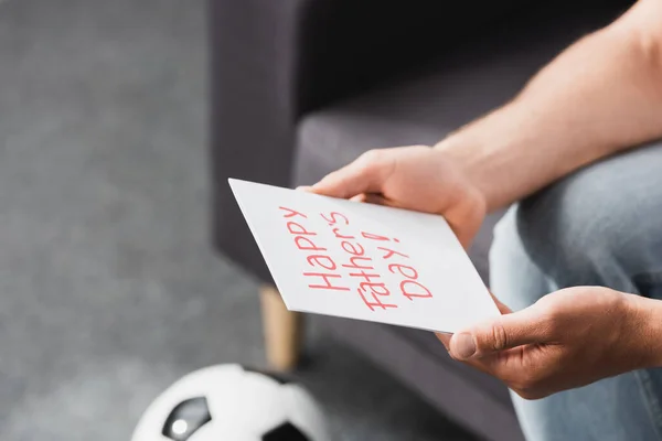 Partial view of man holding happy father day card near soccer ball — Stock Photo