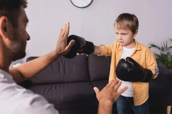 Enfoque selectivo del hombre luchando con el hijo usando guantes de boxeo - foto de stock