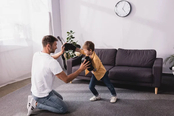 Cute boy in boxing gloves fighting with adorable son on floor — Stock Photo