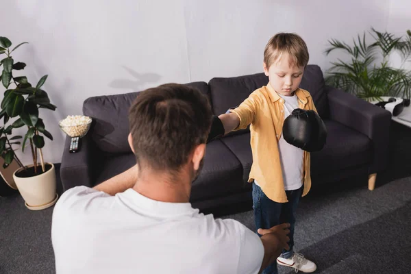 Back view of man fighting with cute son in boxing gloves — Stock Photo