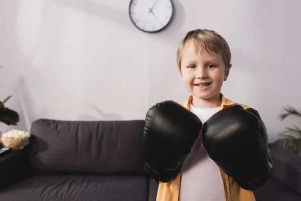 Счастливый мальчик в боксёрских перчатках улыбается, глядя в камеру — стоковое фото