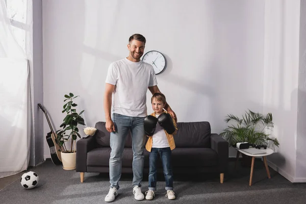 Glücklicher Vater steht neben Sohn in Boxhandschuhen und berührt seine Schulter — Stockfoto