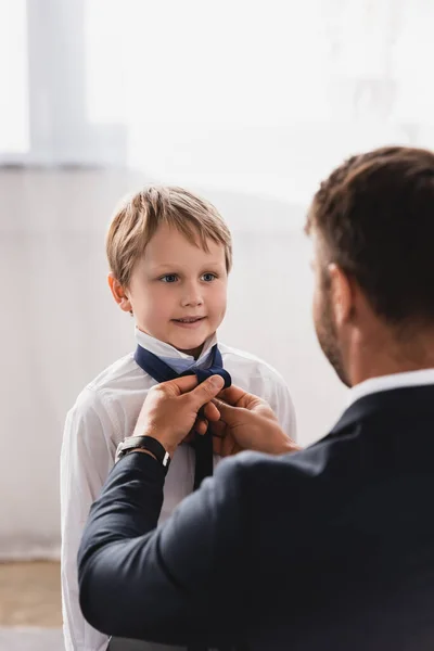 Selective focus of businessman putting tie on smiling, adorable son at home — Stock Photo