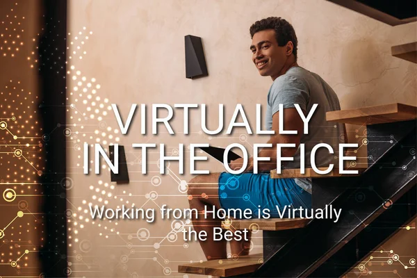 Happy mixed race man using laptop on stairs near virtually in the office, working from home is virtually the best lettering — Stock Photo