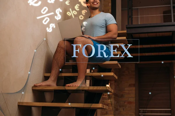 Vista recortada del hombre de raza mixta utilizando el ordenador portátil en las escaleras cerca de letras forex - foto de stock