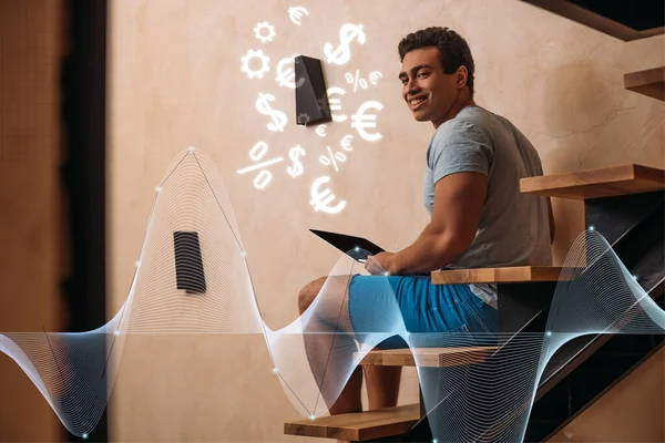 Happy mixed race man using laptop on stairs near dollar and euro signs — Stock Photo