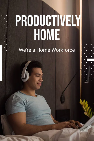 Bi-racial man listening music in headphones and using laptop near productively home, were a home workforce lettering — Stock Photo