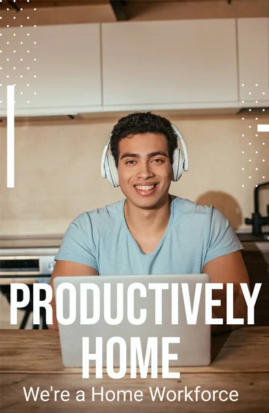 Smiling bi-racial man listening music in headphones and using laptop near productively home, were a home workforce lettering — Stock Photo