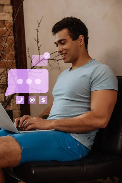 Sorridente freelance razza mista utilizzando laptop vicino bolla discorso virtuale con chat — Foto stock