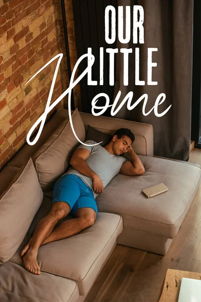 Mixed race man sleeping on sofa near book and our little home lettering — Stock Photo
