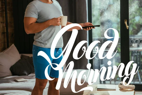 Vue recadrée de l'homme avec tasse de café tenant télécommande près de lettrage bon matin — Photo de stock