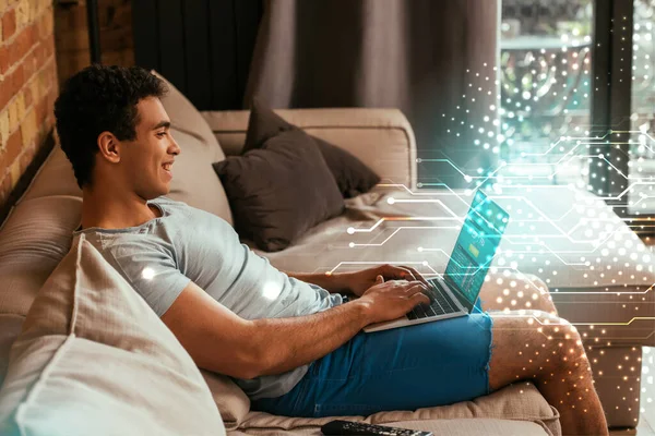 Homem de raça mista feliz refrigeração e usando laptop com site SportsBet na tela perto da ilustração digital — Fotografia de Stock