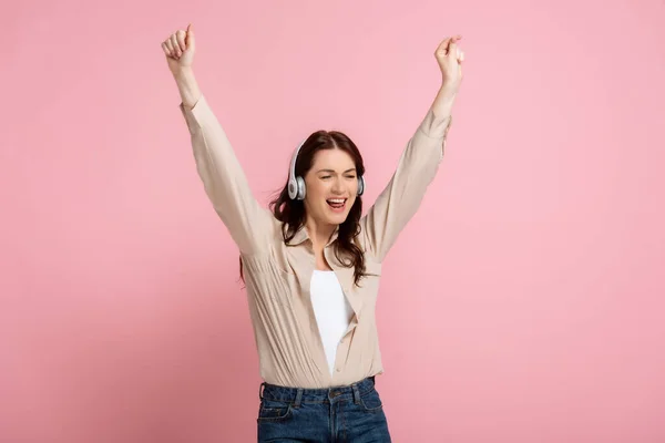 Beautiful happy woman dancing in headphones on pink background, concept of body positive — Stock Photo