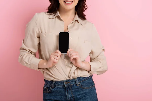 Ausgeschnittene Ansicht einer lächelnden brünetten Frau mit Smartphone und leerem Bildschirm auf rosa Hintergrund — Stockfoto
