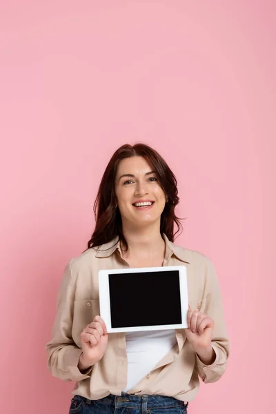 Bella donna sorridente in possesso di tablet digitale con schermo bianco su sfondo rosa — Foto stock