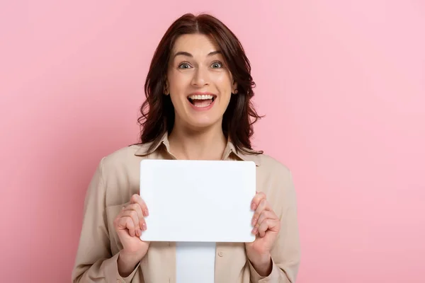 Positive woman looking at camera while holding empty card on pink background — Stock Photo