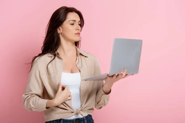 Bella donna bruna che tiene il computer portatile su sfondo rosa — Foto stock