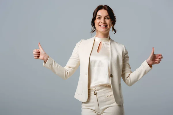 Beautiful smiling businesswoman showing thumbs up and looking at camera isolated on grey — Stock Photo