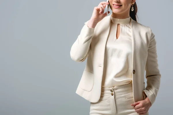 Ausgeschnittene Ansicht einer lächelnden Geschäftsfrau, die auf einem Smartphone spricht, isoliert auf grau — Stockfoto