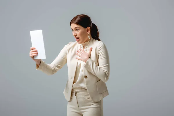 Femme d'affaires choquée ayant appel vidéo sur tablette numérique isolé sur gris, concept de corps positif — Photo de stock