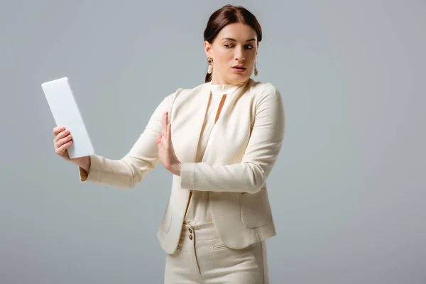 Захищена бізнес-леді показує стоп- жест, маючи відеодзвінок на цифровому планшеті ізольовано на сірому — стокове фото