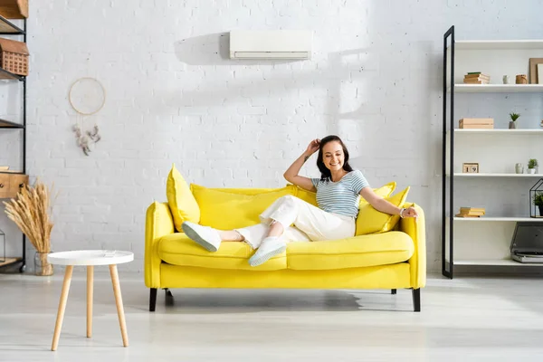Schöne lächelnde Frau sitzt auf Couch im Wohnzimmer — Stockfoto