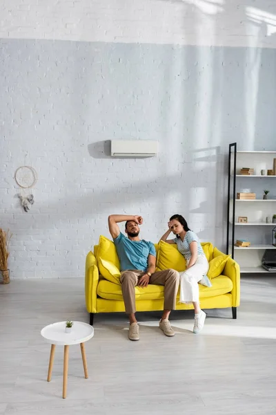 Tired couple suffering from heat on sofa in living room — Stock Photo