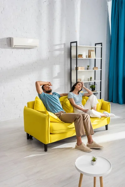 Mann leidet unter Hitze nahe müder Freundin auf Sofa zu Hause — Stockfoto