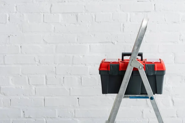 Toolbox on metal ladder near white wall — Stock Photo