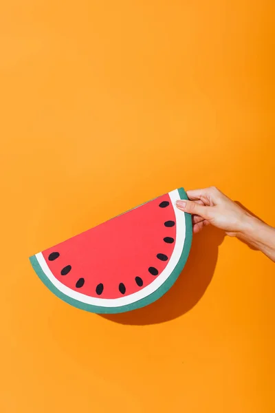 Cropped view of girl holding paper cut watermelon on orange — Stock Photo