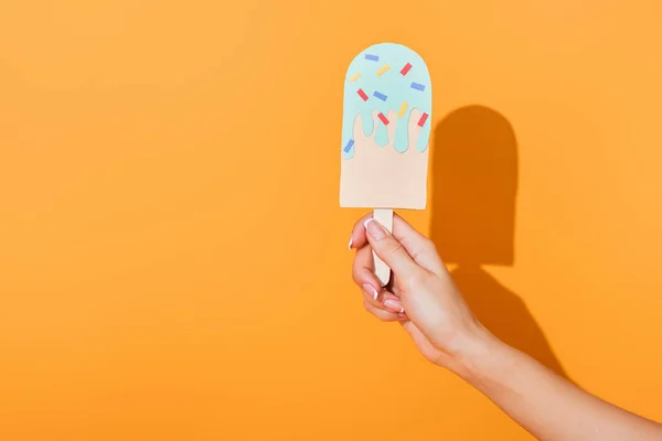 Vista ritagliata di giovane donna che tiene il gelato tagliato su carta arancione — Foto stock