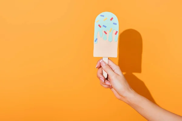 Vista recortada de la mujer joven sosteniendo papel helado cortado en naranja - foto de stock