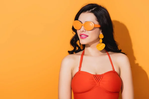 Ragazza elegante in occhiali da sole e costume da bagno su arancione — Foto stock
