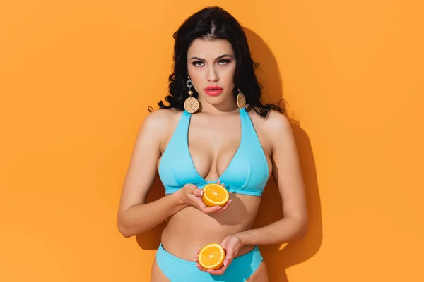 Schöne Frau im Badeanzug mit Fruchthälften auf Orange — Stockfoto