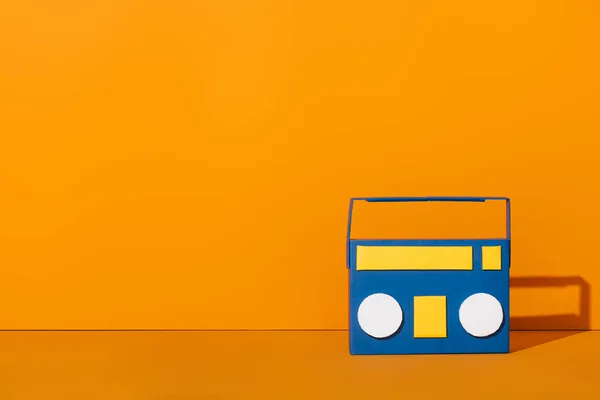 Blue paper cut boombox on orange with copy space — Stock Photo